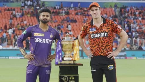 Two cricketers posing with championship trophy at stadium.