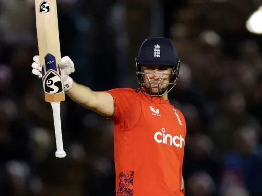 Cricketer celebrating with bat in night match.