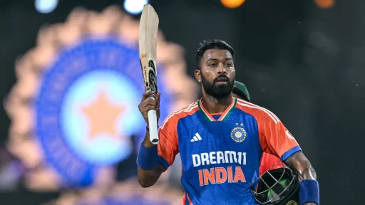 Cricketer in blue jersey holding bat with stadium lights