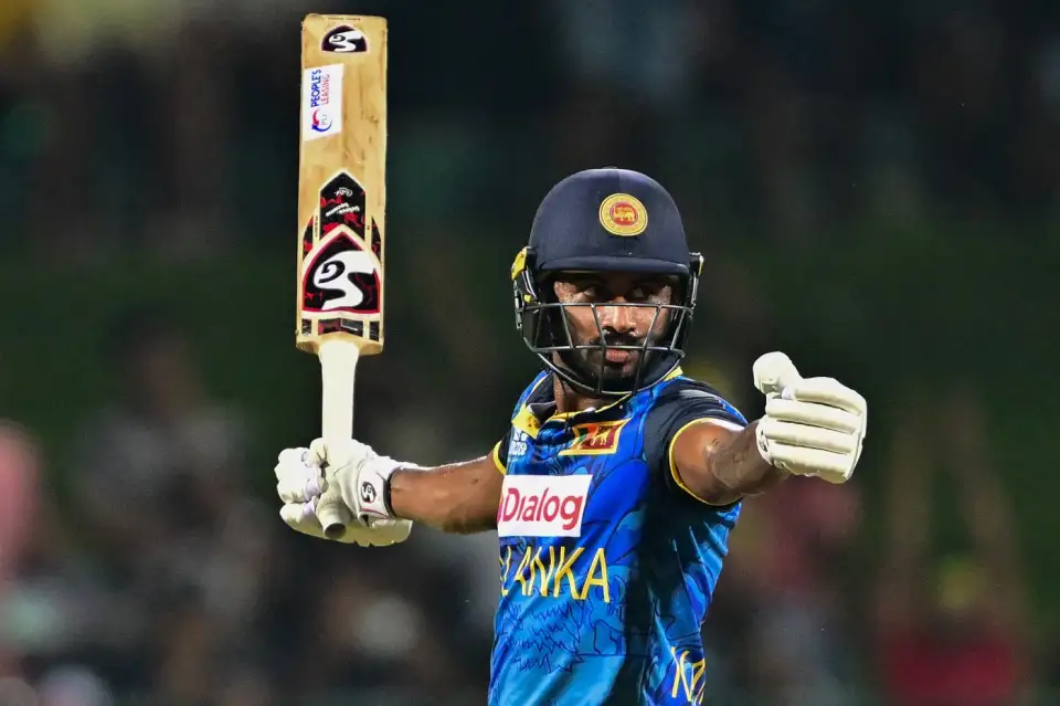 Cricketer raising bat celebrating victory at night game