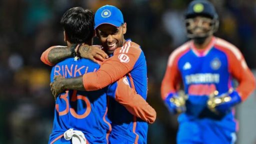 Two cricketers celebrating victory with a hug on field