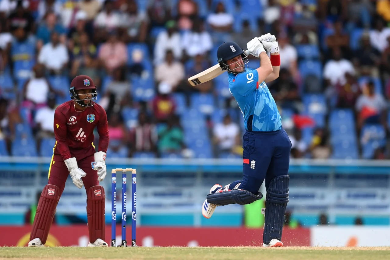 Cricketer hitting ball during match, wicketkeeper behind