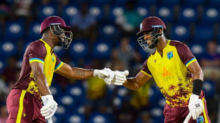 Two cricketers fist-bumping during a match