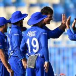 Cricket team in blue celebrates on field