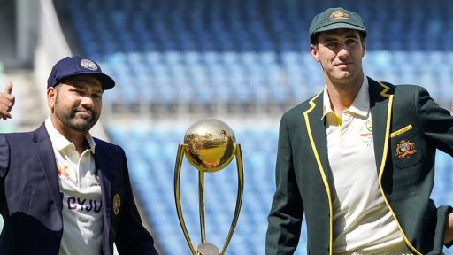 Two cricket players with trophy on sunny stadium field