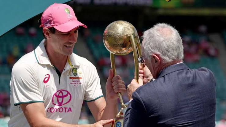 Cricketer receiving trophy from an older man on field