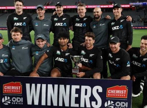 Cricket team celebrating with trophy at stadium.