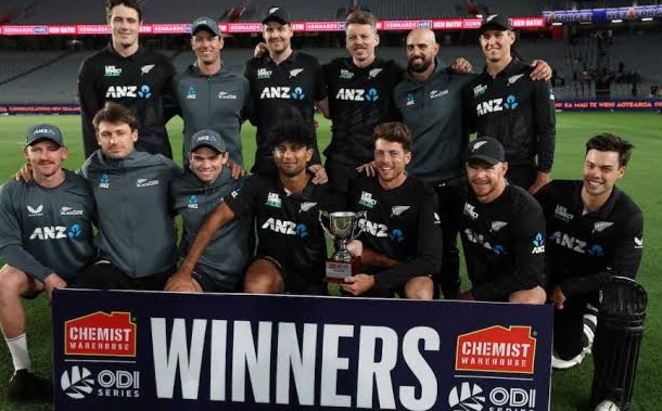 Cricket team celebrating with trophy at stadium.