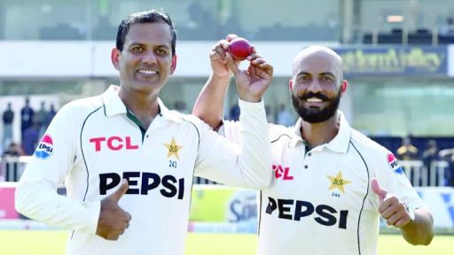 Two cricket players celebrating with a red ball