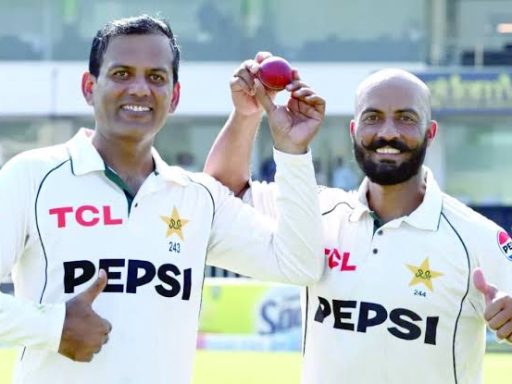 Two cricket players celebrating with a red ball