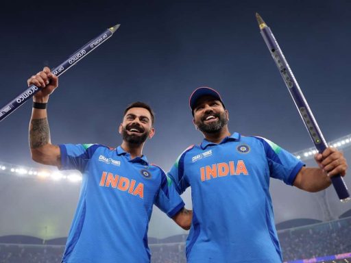 Two Indian cricketers celebrating with oversized pencils